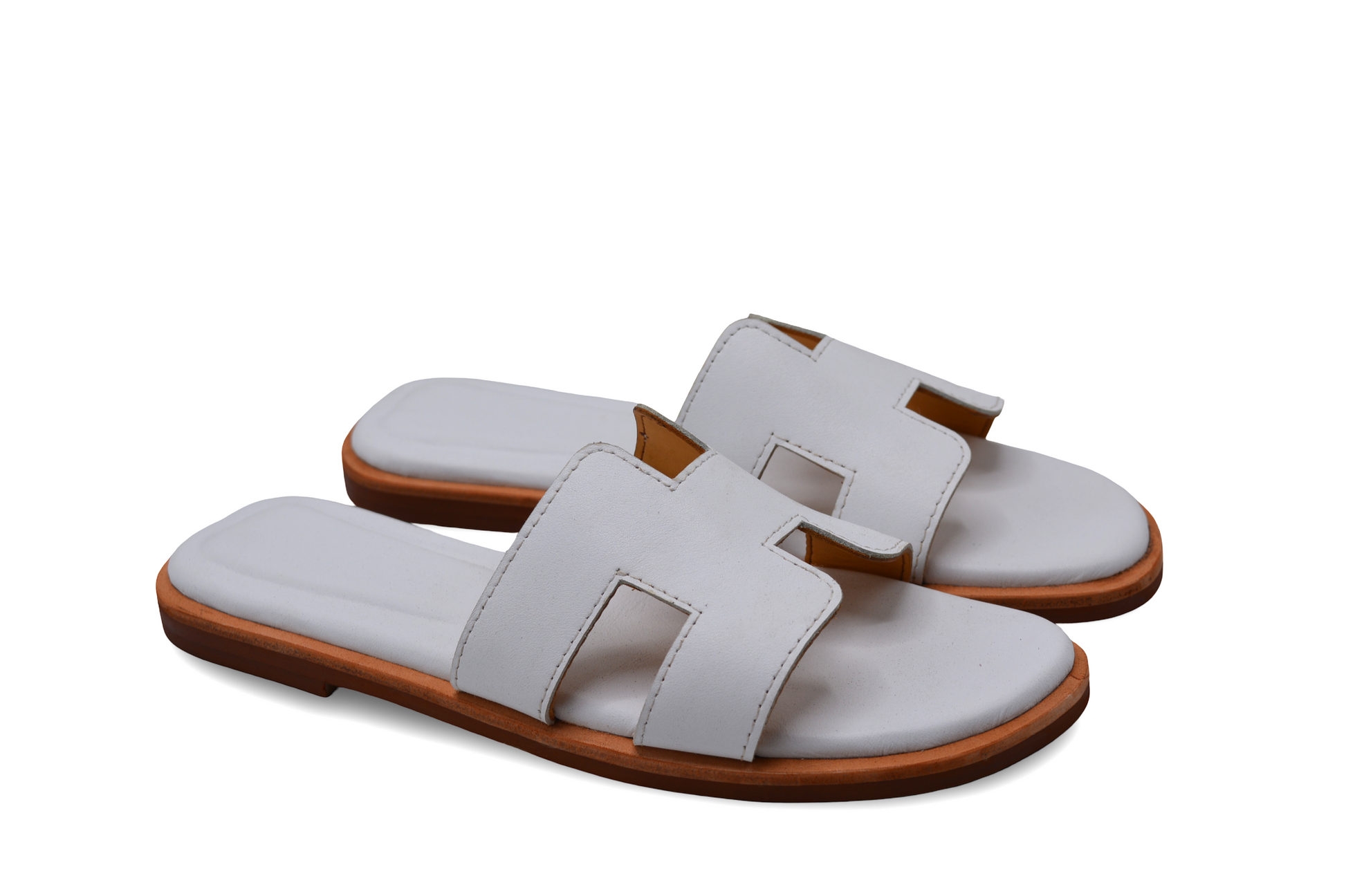Pair of white sandals with brown soles on a white background